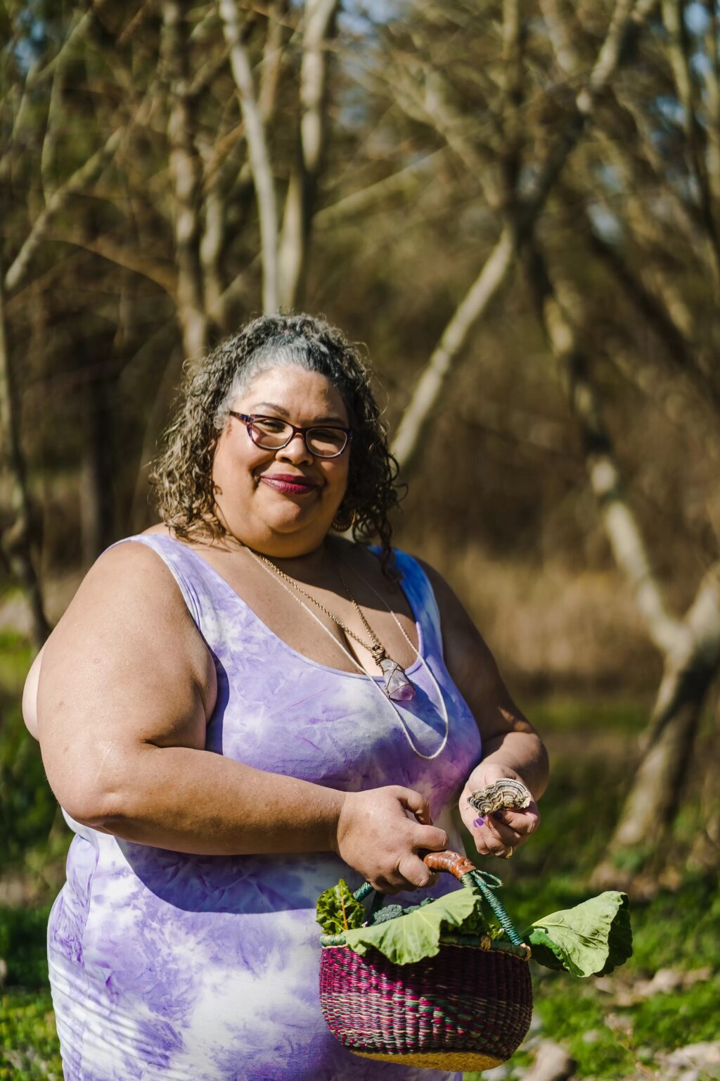 A picture of a smiling woman holding a basket of vegetables.
